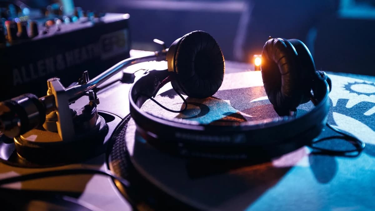 Ein Kopfhörer liegt auf dem Mischpult eines DJ-Arbeitsplatzes in blauem Licht. Foto: Gigxels / Pixabay.