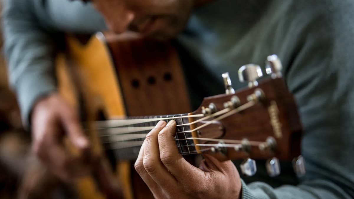 Ein Musiker stimmt die offene Mechanik einer Konzertgitarre. Foto: MaliAroestiPhotography / Pixabay.