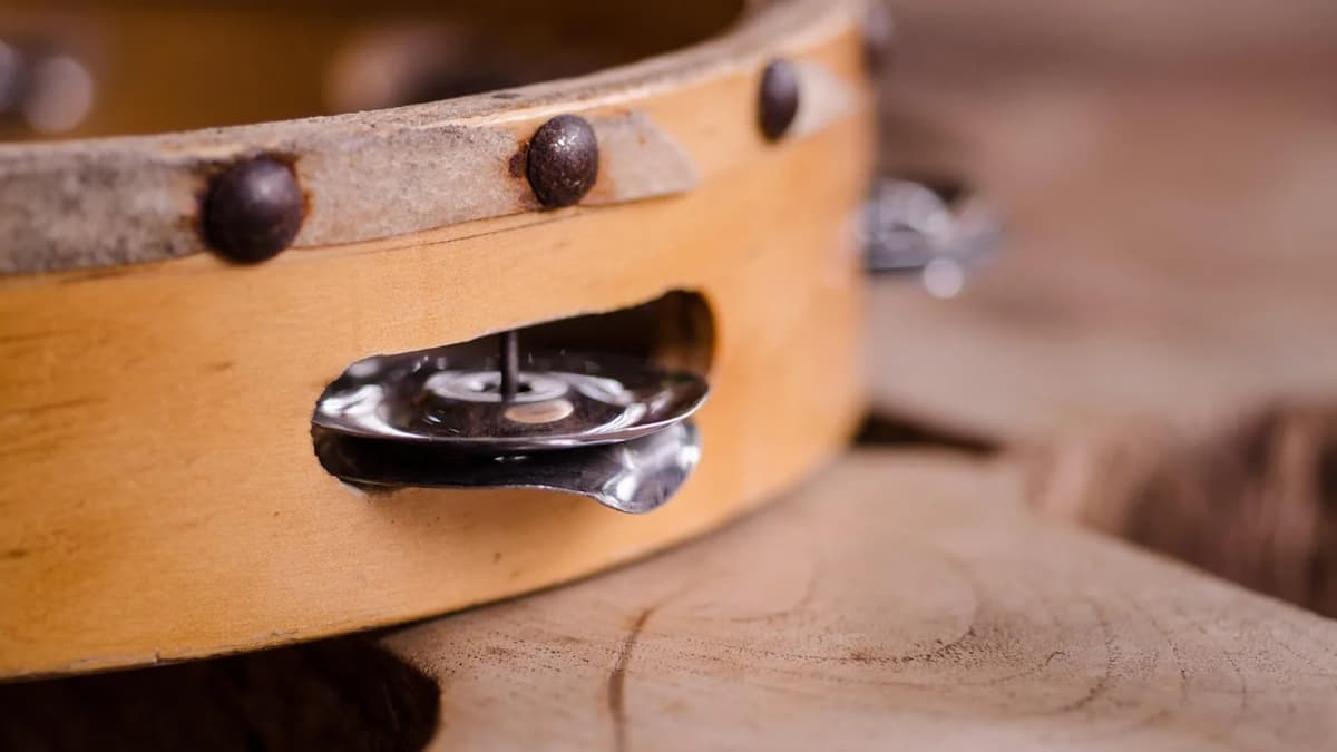Ein Tamburin mit Schellen liegt auf einer Holzfläche. Foto: ClickerHappy / Pixabay.