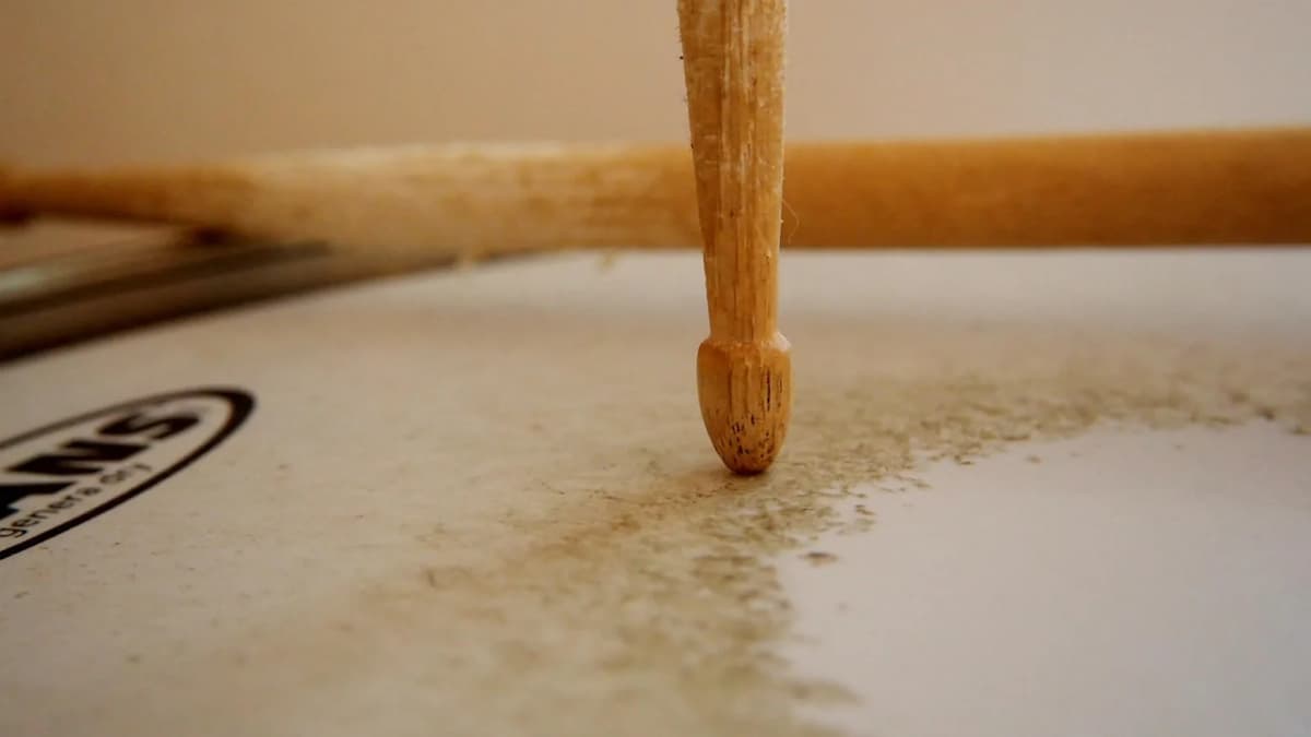 Die Spitze eines Drumsticks auf einem abgespielten, sichtbar verschlissenen Trommelfell. Foto: flockine / Pixabay.