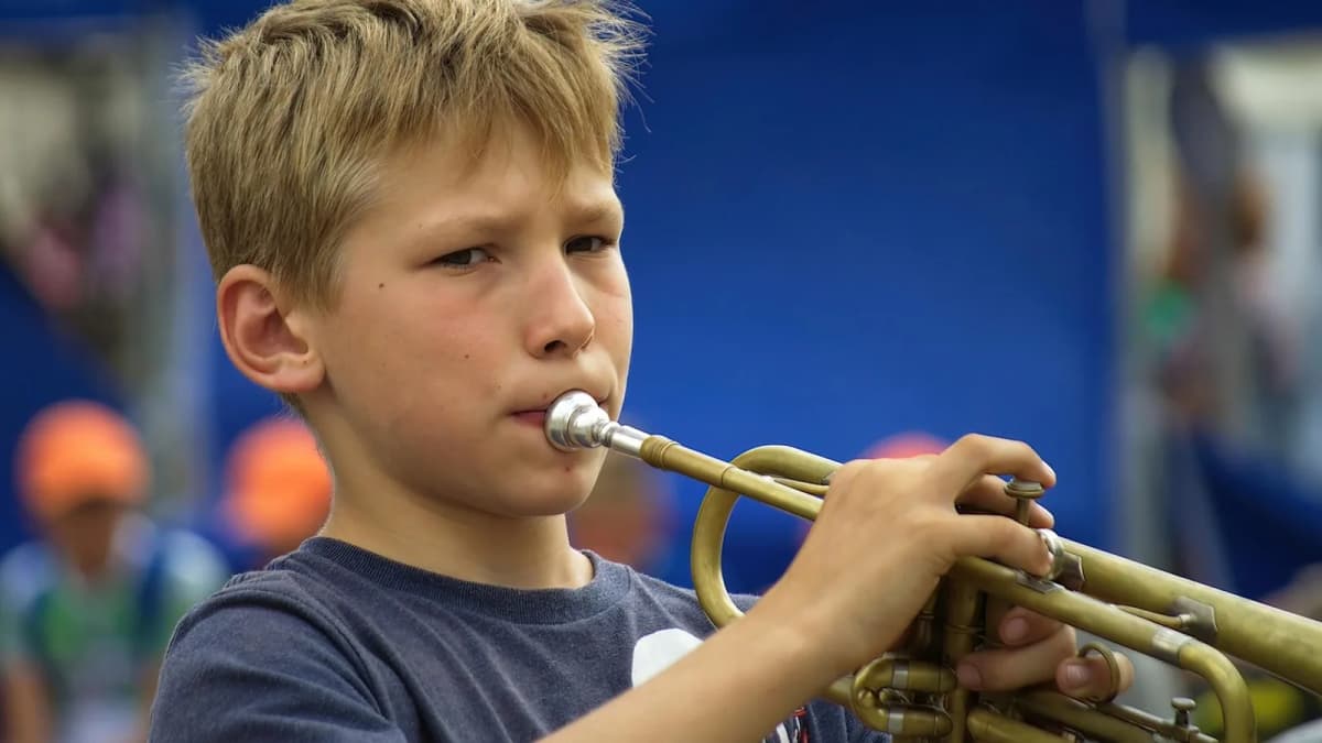 Ein Junge spielt konzentriert Trompete im Freien. Foto: Surprising_Media / Pixabay.